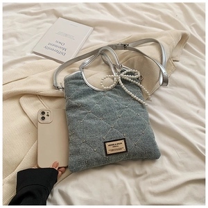 Détail du sac cabas en denim gris avec motif matelassé et breloque nœud en perles