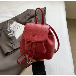 Detailed close-up of red pebbled leather mini backpack with drawstring and silver orb charm