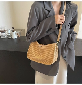 Detail of woven texture and gold buckles on a stylish crossbody straw bag for women