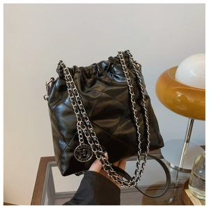 Close-up of black quilted bucket bag featuring drawstring closure and silver chain strap