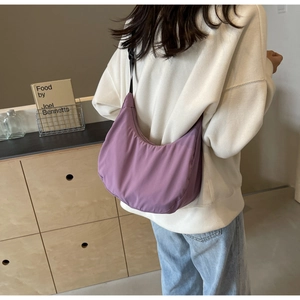 Back view of a model wearing a purple nylon hobo bag in a cozy indoor setting