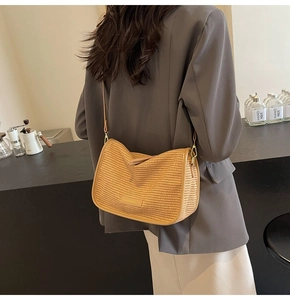 Detail showing woven texture of a light brown crossbody bag paired with a gray blazer