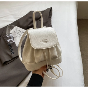 Close-up of white mini backpack featuring lychee texture leather and silver ball drawstrings