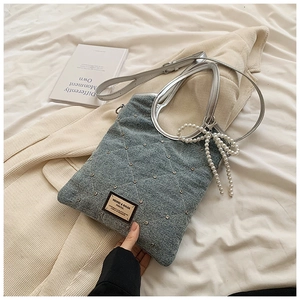 Détail du sac en jean matelassé avec clous argentés et nœud en perles élégant