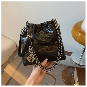 Detailed view of the quilted bucket bag with chain strap and silver logo pendant