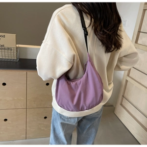 Close-up of a purple nylon dumpling bag with an adjustable black shoulder strap