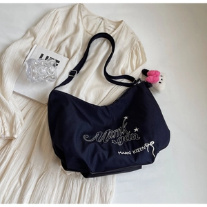 Dettaglio della borsa a tracolla in nylon blu scuro con ricamo bianco e ciondolo a gatto peluche