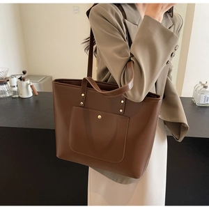Detail showing the brown faux leather tote bag with elegant golden hardware and exterior pocket