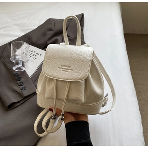 Close-up of cream lychee leather mini backpack featuring drawstring and metal bead details