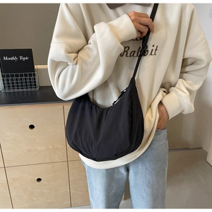 Detail of a black nylon crescent hobo bag styled with a casual sweater and jeans