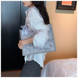 Gros plan d'un grand sac cabas gris avec broderie florale et un foulard en soie décoratif