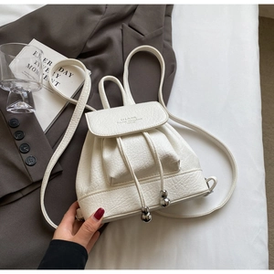 Detail of cream white mini backpack with lychee texture and metallic sphere drawstrings