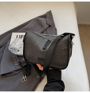 Detail of woven square bag with dual black straps and long tassel zipper on a grey suit