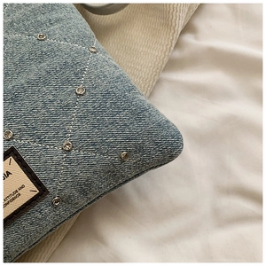 Détail d'un sac en denim bleu clair avec surpiqûres blanches et strass étincelants