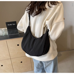 Close-up of black nylon crescent bag showing adjustable strap and drape on shoulder