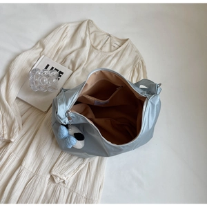 Dettaglio borsa tote in raso azzurro con fodera interna e ciondolo panda peluche