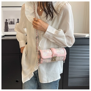 Detail of pink cylinder crossbody bag with woven chain strap on a fashion model