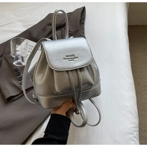 Close-up of metallic silver mini backpack with drawstring and debossed text detail