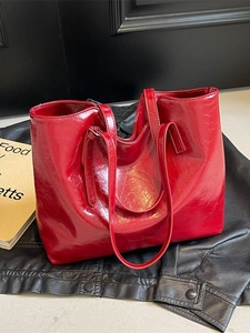 Large red tote bag in crinkled patent leather for women on a dark background