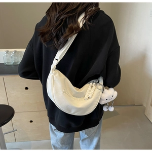 Détail du sac bandoulière blanc en demi-lune avec broderie et breloque nuage