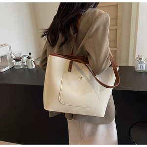 Large cream tote bag with brown trim shown from back angle on a female model