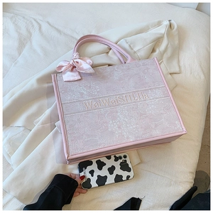 Détail de la broderie florale et de la sangle rose sur le grand sac cabas tissé élégant