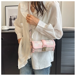 Close-up of pink jacquard cylinder bag with leather trim and silver chain strap detail