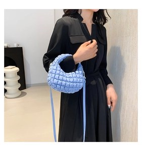 Detail of light blue quilted puffer bag showing the soft fabric texture and strap