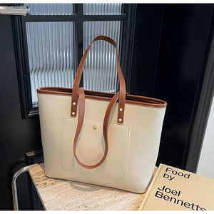 Detail of minimalist tote bag with cream-brown leather stitching and gold buckle hardware