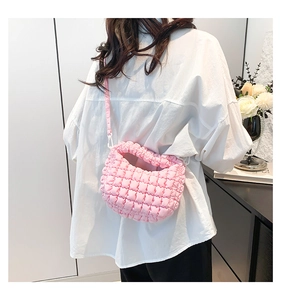 Detail of pink quilted dumpling bag showing textured nylon fabric and adjustable strap