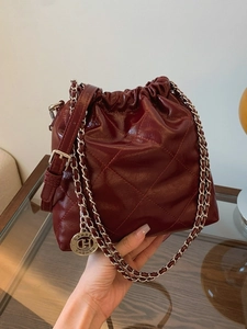 Deep red quilted bucket bag with shiny leather texture and elegant metal chain strap