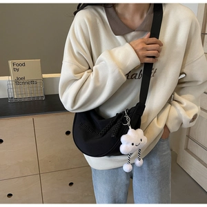 Détail du sac dumpling en nylon noir avec breloque nuage en peluche et zip en corde