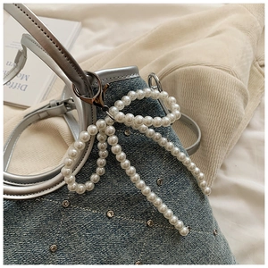 Détail du sac cabas en denim avec strass brillants et grand nœud en perles blanches