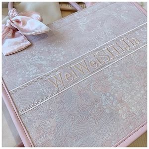 Détail du sac cabas rose brodé avec motifs floraux et nœud en ruban de soie