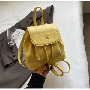 Macro detail of yellow pebbled leather backpack showing drawstring and flap closure
