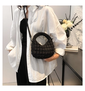 Macro shot of black quilted puff handbag texture with elegant detachable crossbody strap
