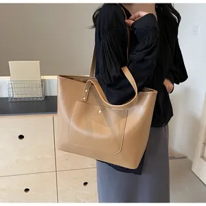 Close-up of brown faux leather tote bag with front pocket and gold metal rivets