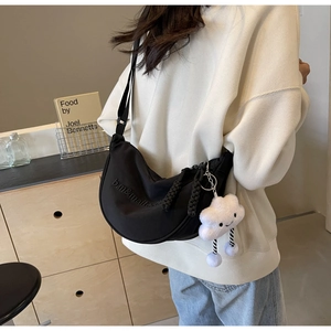 Détail du sac bandoulière en nylon noir avec pendentif nuage en peluche sur un mannequin