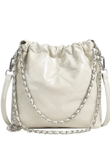 Stylish cream quilted bucket bag with chain strap and metallic charm on white background