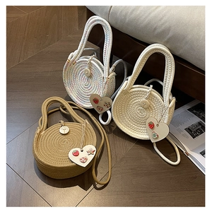 Detail view of woven round bags in cream and khaki with decorative heart charms