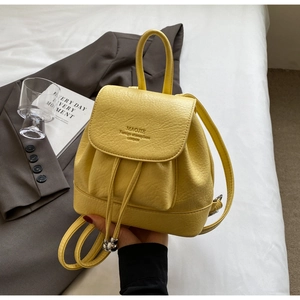 Detail of yellow pebbled leather mini backpack with drawstring and flap closure