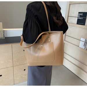 Detail shot of khaki tote bag featuring a front pocket and elegant gold metal hardware