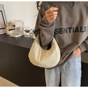 Detail of minimalist nylon hobo bag in beige shown in a cozy lifestyle setting