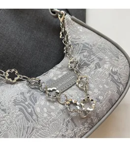 Détail du tissu jacquard gris avec motifs de paysages et chaîne florale en métal argenté