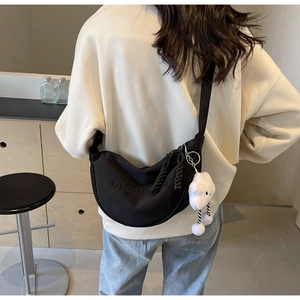 Détail d'un sac demi-lune en nylon noir avec un pendentif nuage en peluche mignon