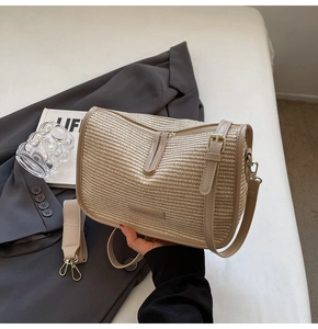 Detail of beige woven crossbody bag with dual zipper closure and metal logo plaque