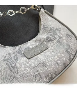 Gros plan du sac à main en jacquard gris avec chaîne métallique florale argentée élégante