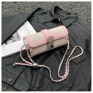 Detailed shot of pink cylinder crossbody bag with embroidered fabric and metal chain strap