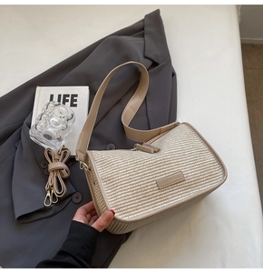 Detail of beige woven crossbody bag with leather trim on a stylish blazer background