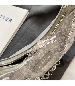 Détail de la fermeture éclair argentée et logo sur le sac en dentelle grise
